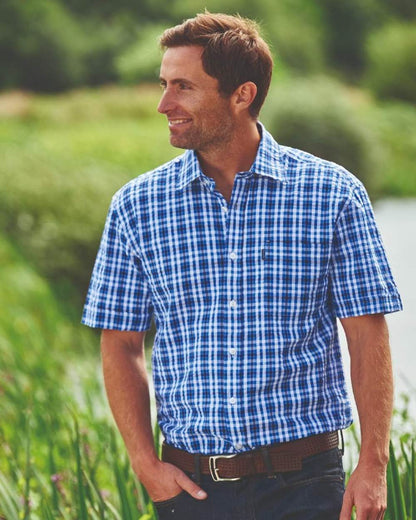 Blue coloured Champion Croyde Cotton Short Sleeved Shirt on blurry green background 