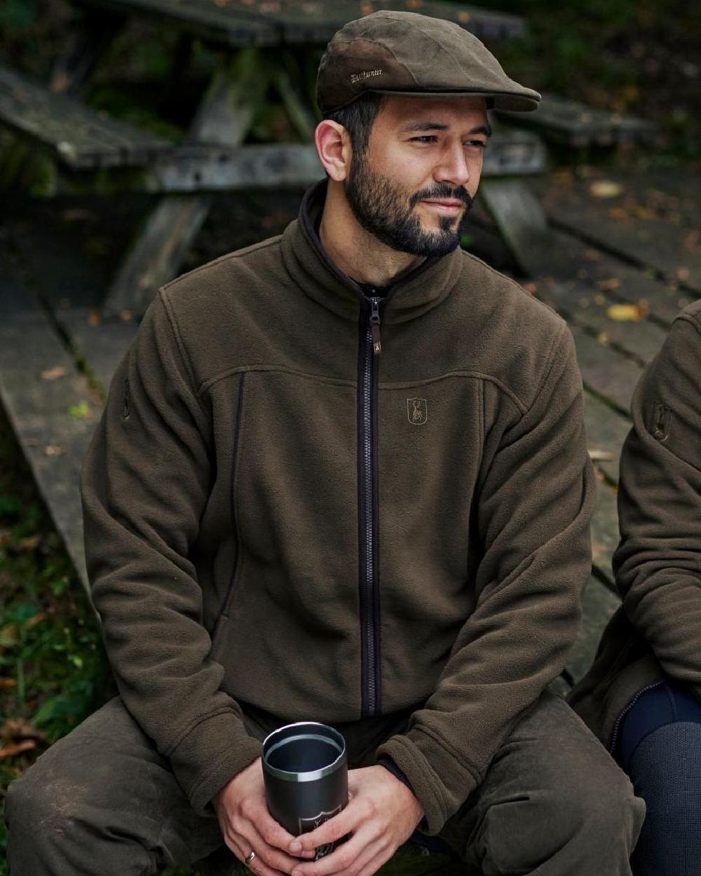 Tarmac Green coloured Deerhunter Eagle Flat Cap on wooden bench background 