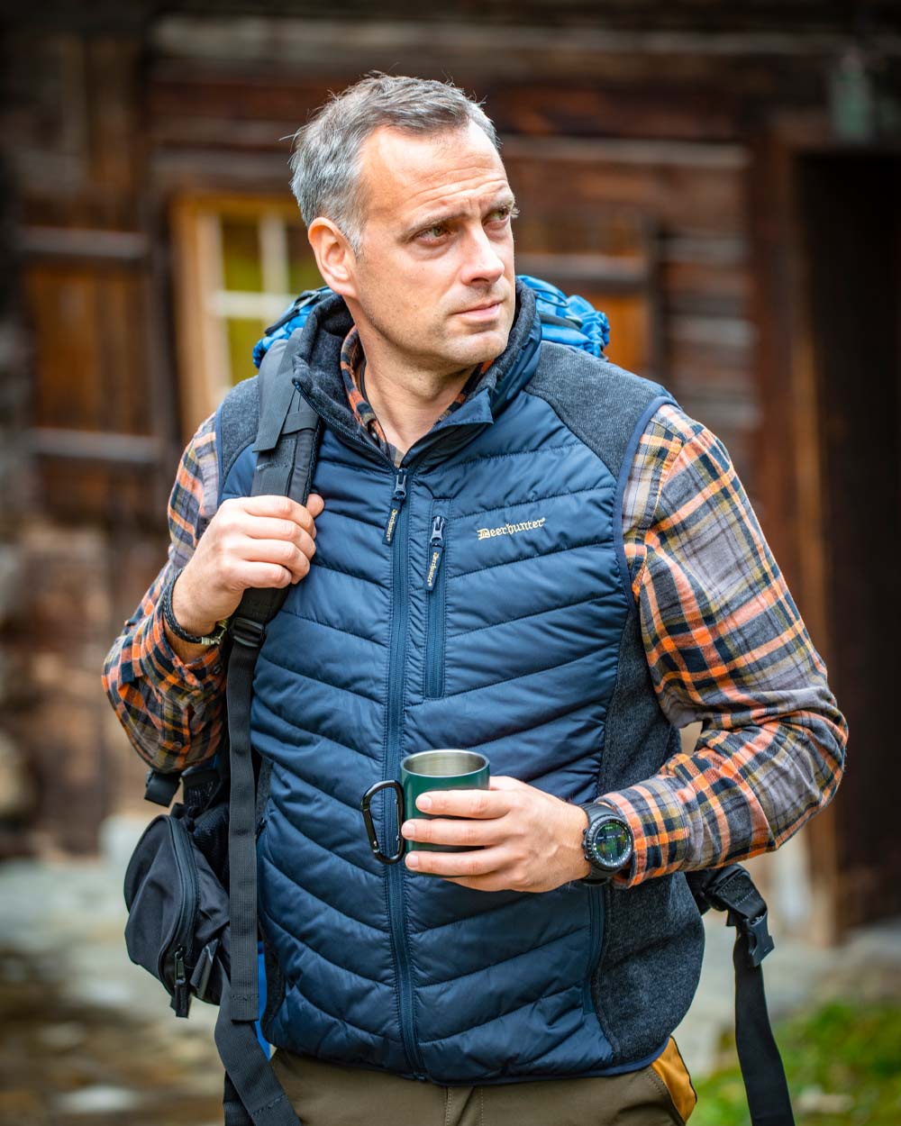 Dark Blue coloured Deerhunter Moor Padded Waistcoat with Knit on Cabin background 