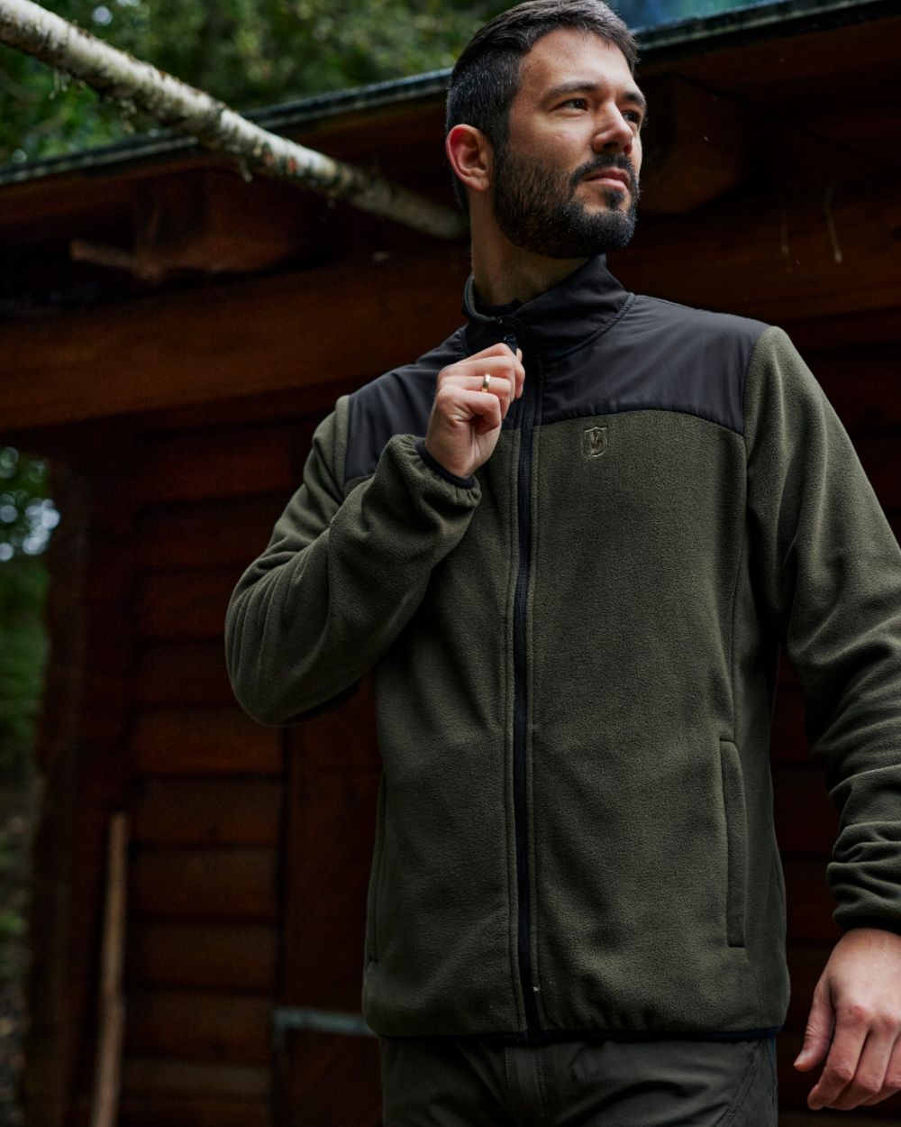 Rifle Green coloured Deerhunter Northward Fleece Jacket on Blurry Cabin background 