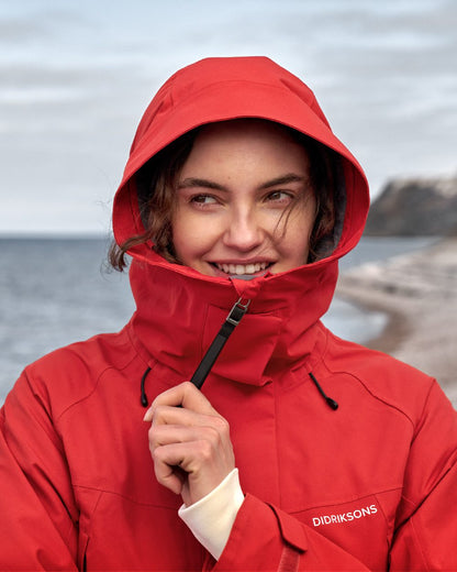 Pomme Red coloured Didriksons Womens Parka on beach background 