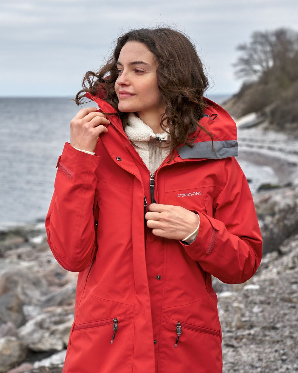 Pomme Red coloured Didriksons Womens Parka on beach background 