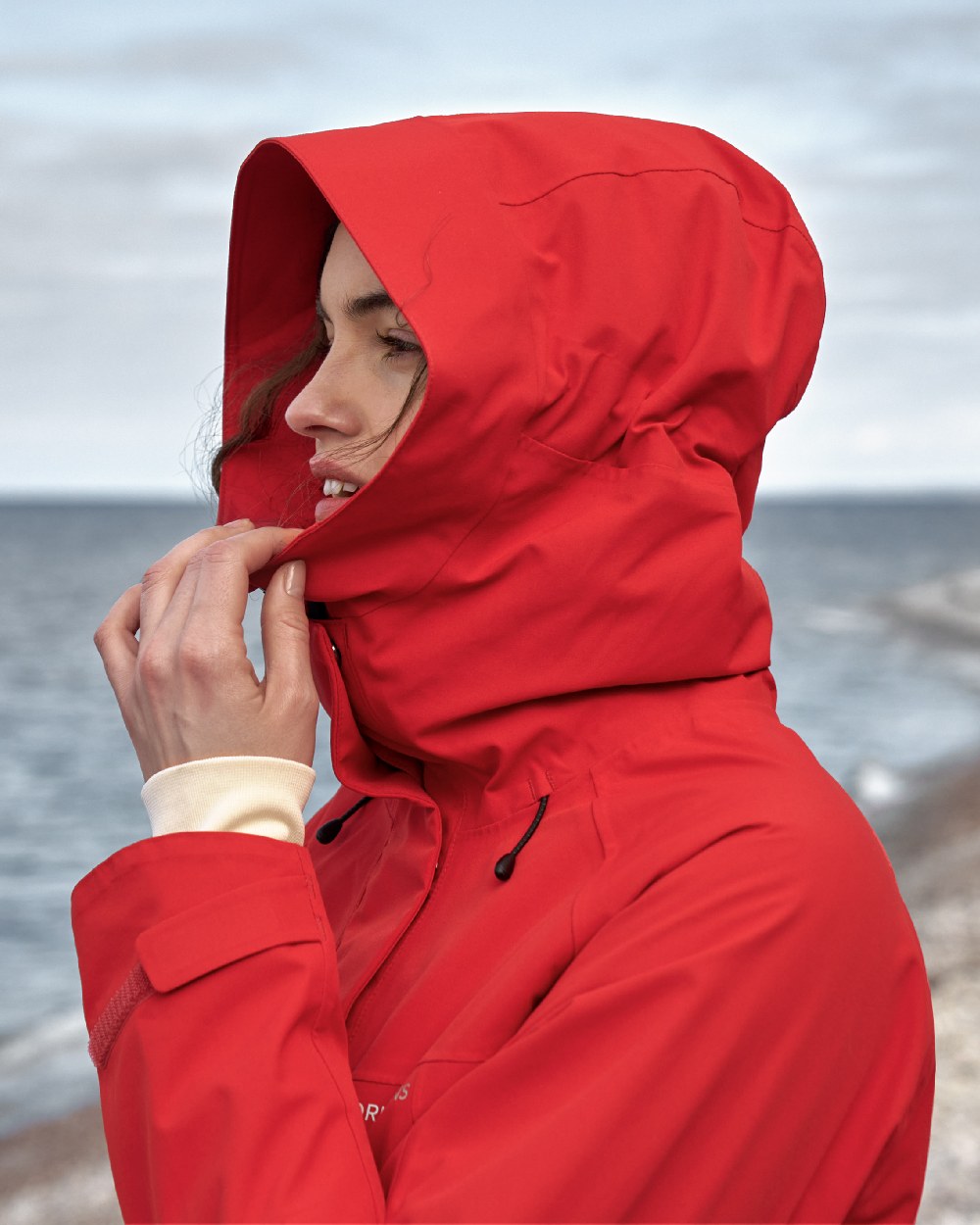 Pomme Red coloured Didriksons Womens Parka on beach background 