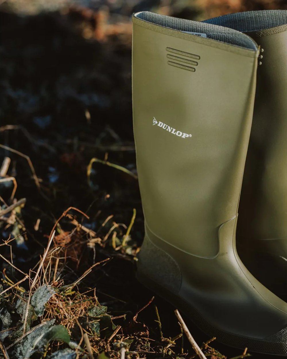 Green coloured Dunlop Pricemastor Wellingtons on blurry background 