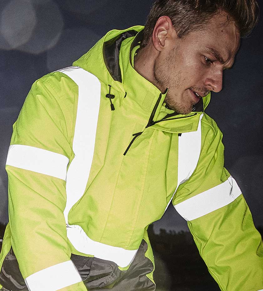 Farmer wears yellow hi-vis jacket with reflective strips.