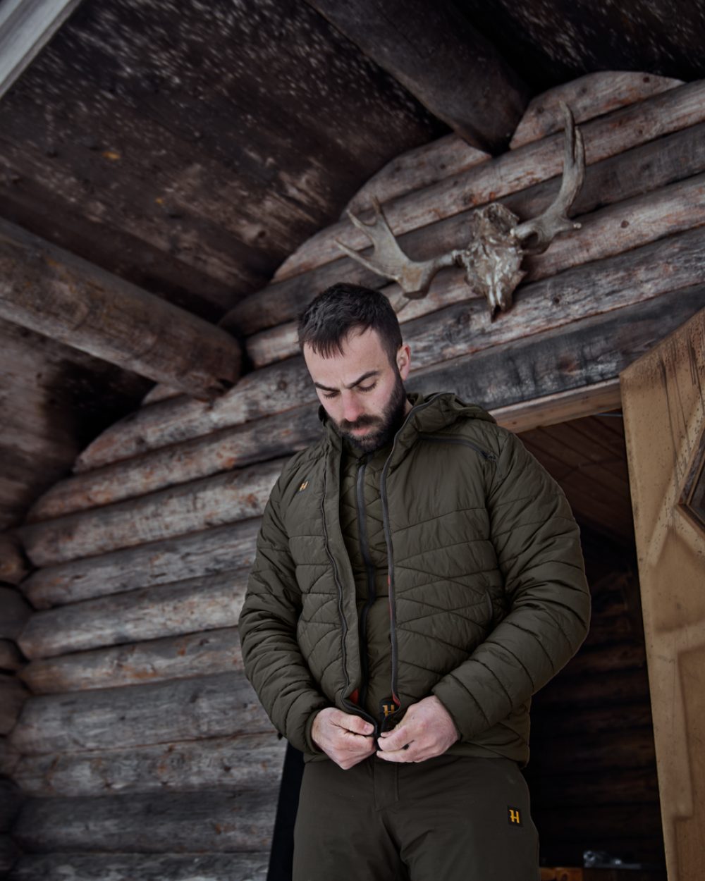 Willow Green Coloured Harkila Logmar Insulated Packable Hooded Jacket on house background 