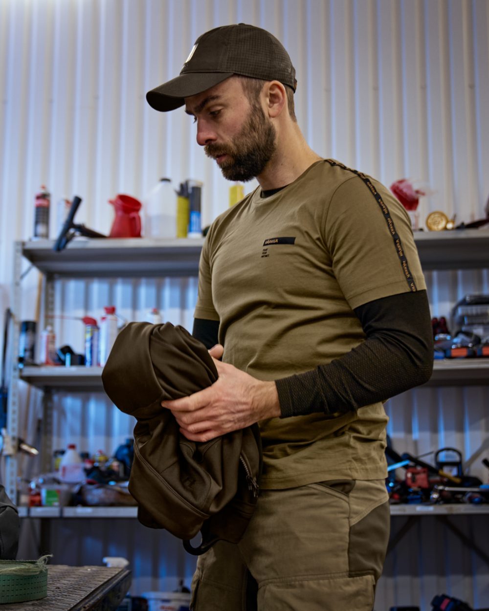 Dark Antique Bronze Coloured Harkila Logo band Short Sleeve T-Shirt On A Workshop Background