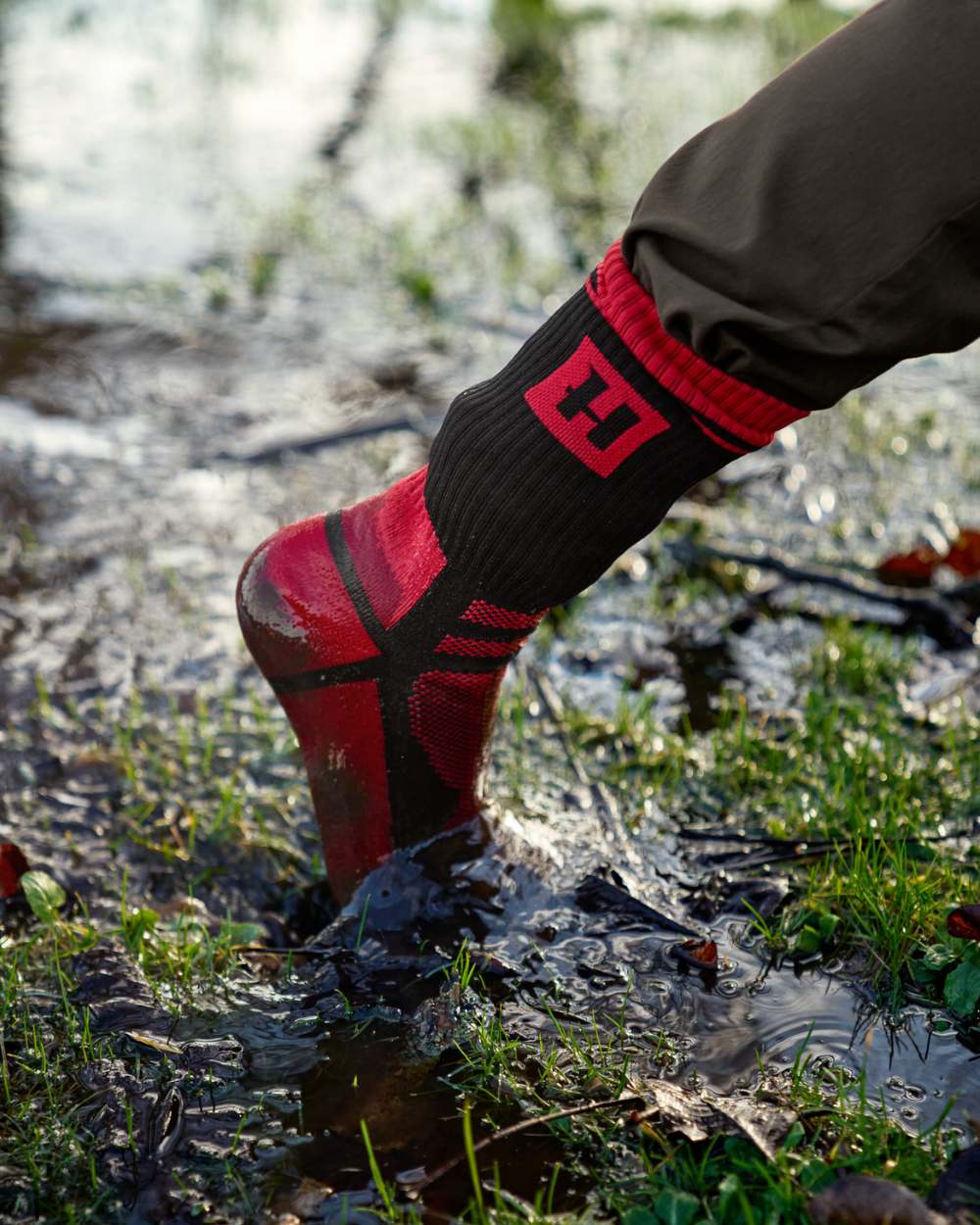 Black Red Coloured Harkila Waterproof Socks On A Forest Background