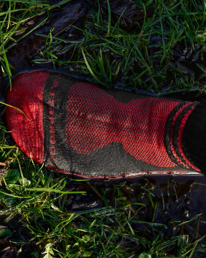 Black Red Coloured Harkila Waterproof Socks On A Forest Background