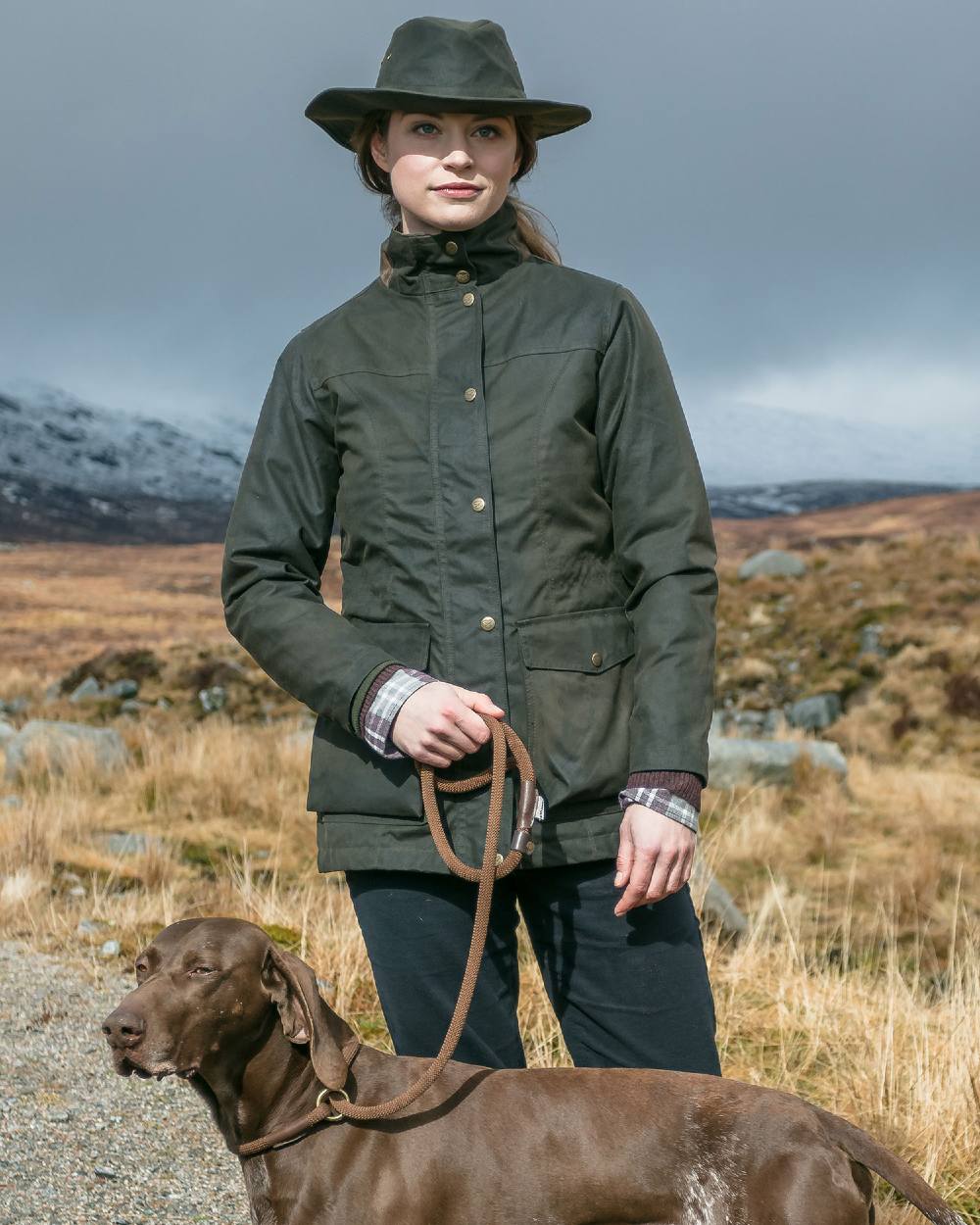 Antique Olive Hoggs of Fife Caledonia Ladies Antique Wax Jacket on model with mountain background 