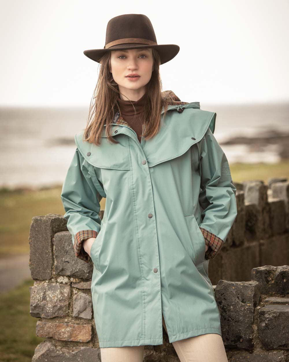 Smoke Blue coloured Jack Murphy Cotswold Ladies Waterproof 3/4 Coat on Blurry Ocean background 