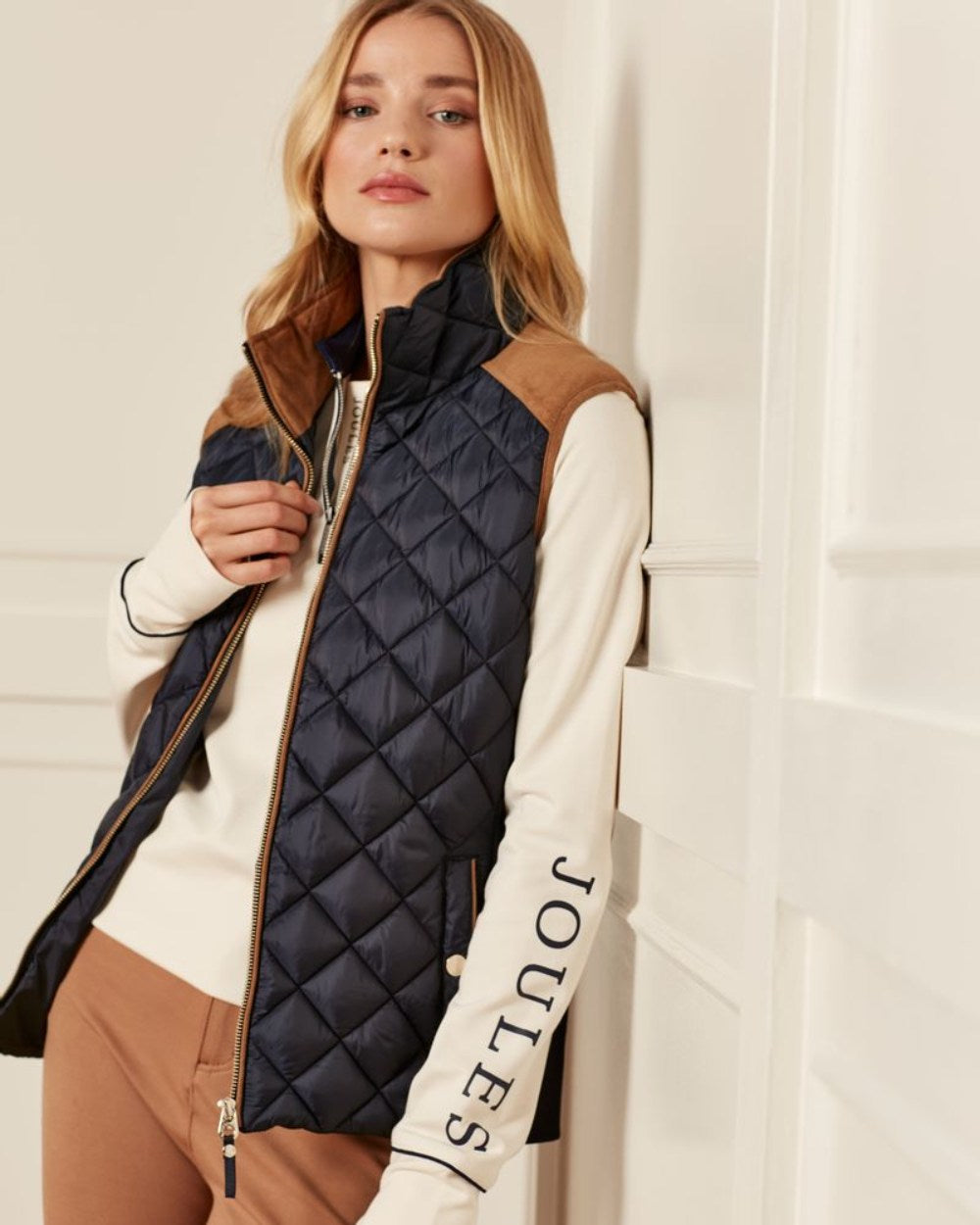 Navy Coloured Joules Braemar Luxe Gilet On A wall Background 