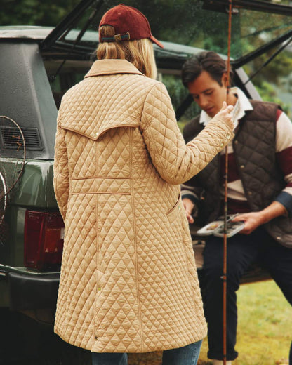 Tan Brown Coloured Joules Rosewell Showerproof Longline Diamond Quilted Coat On A Lake Background 