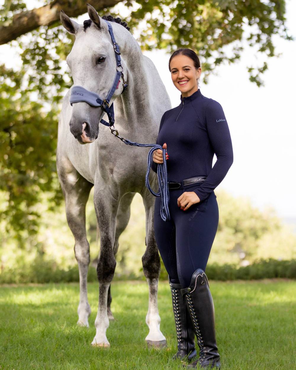 Navy coloured LeMieux Amara II Breech Full Seat with horse in background 