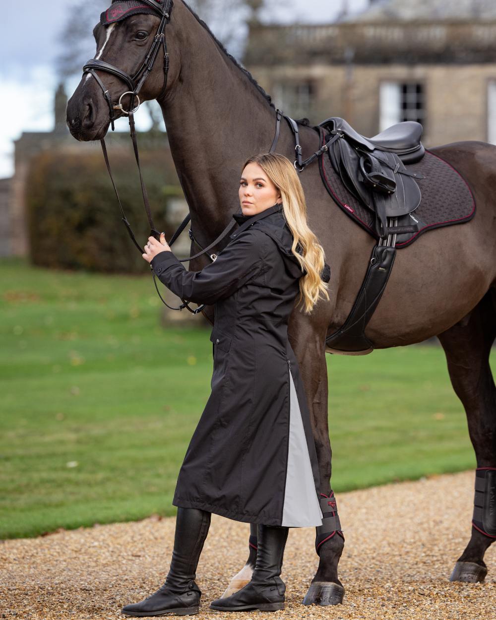 Black Coloured LeMieux Amelie Lightweight Waterproof Riding Coat On A Outer Yard Background 