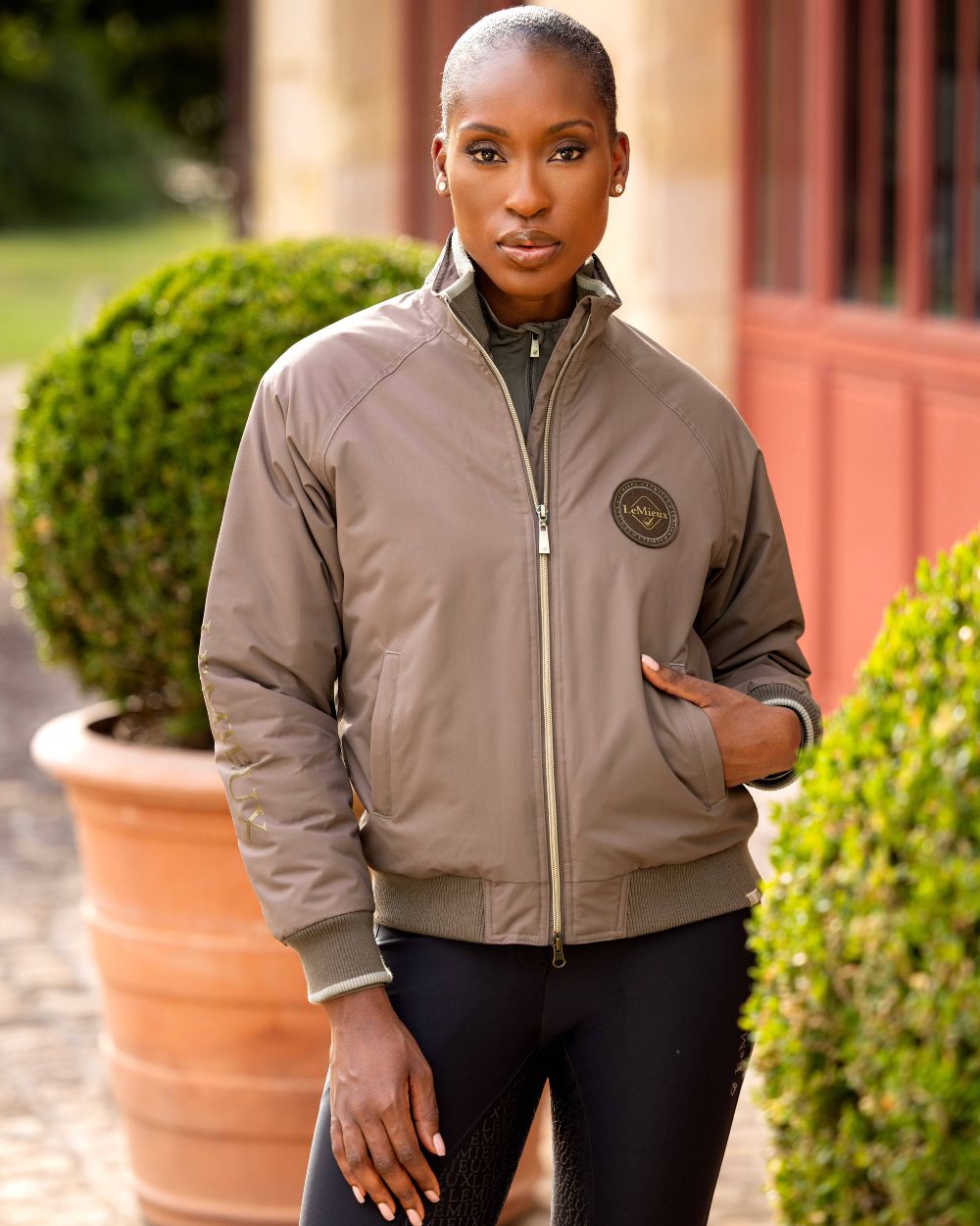 Walnut coloured LeMieux Elite Crew Jacket on blurry building background 