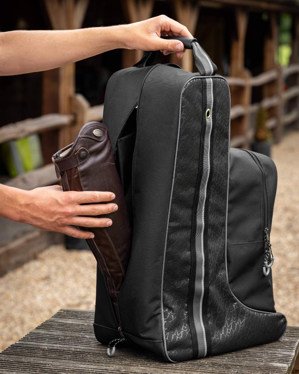 Black coloured LeMieux Elite Pro Boot &amp; Hat Bag on blurry fence background 