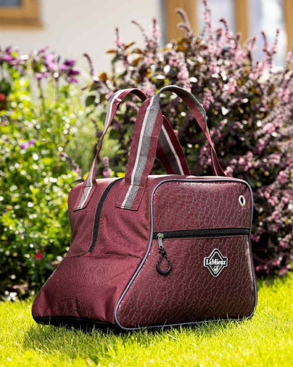 Burgundy coloured LeMieux Elite Pro Short Boot Bag with plant in background 