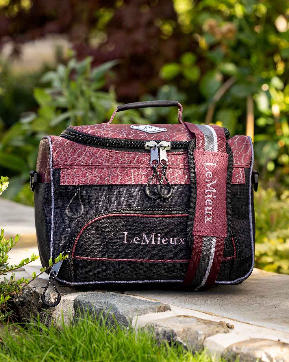Burgundy coloured LeMieux Elite ProKit Lite Grooming Bag with trees in background 