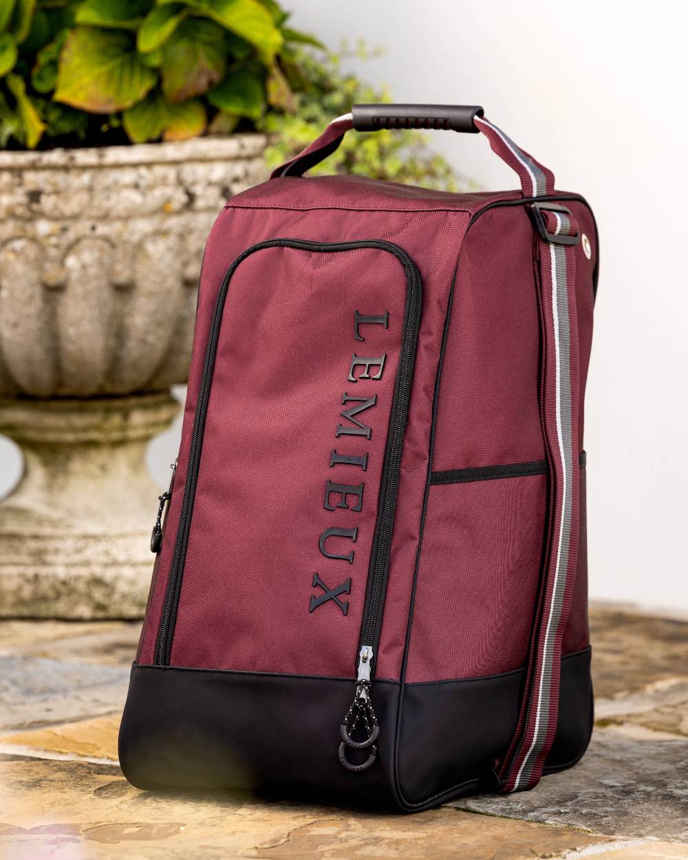 Burgundy coloured LeMieux Elite Wellington Boot Bag on plant background 