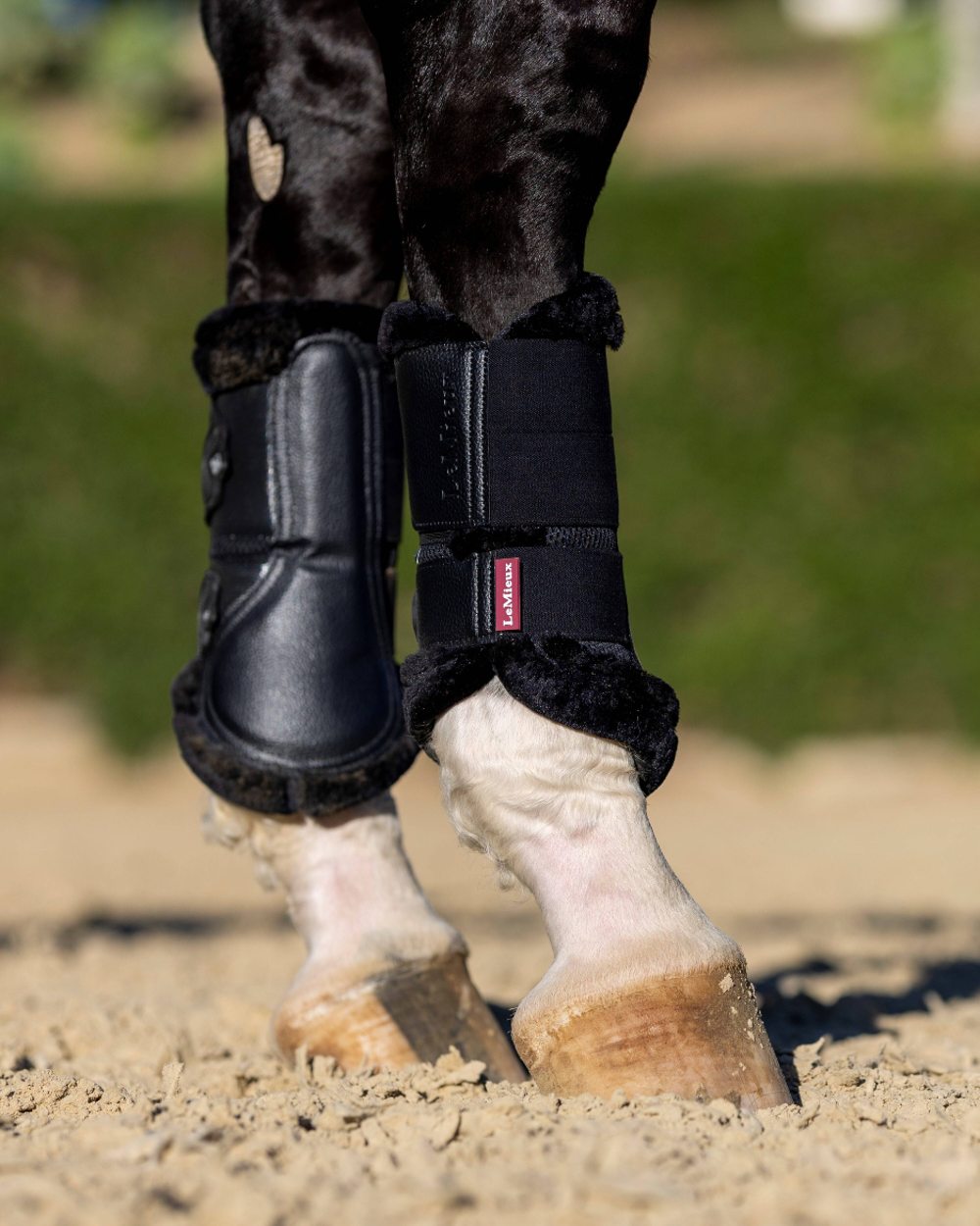 Black coloured LeMieux Fleece Edged Mesh Brushing Boots on blurry green background 