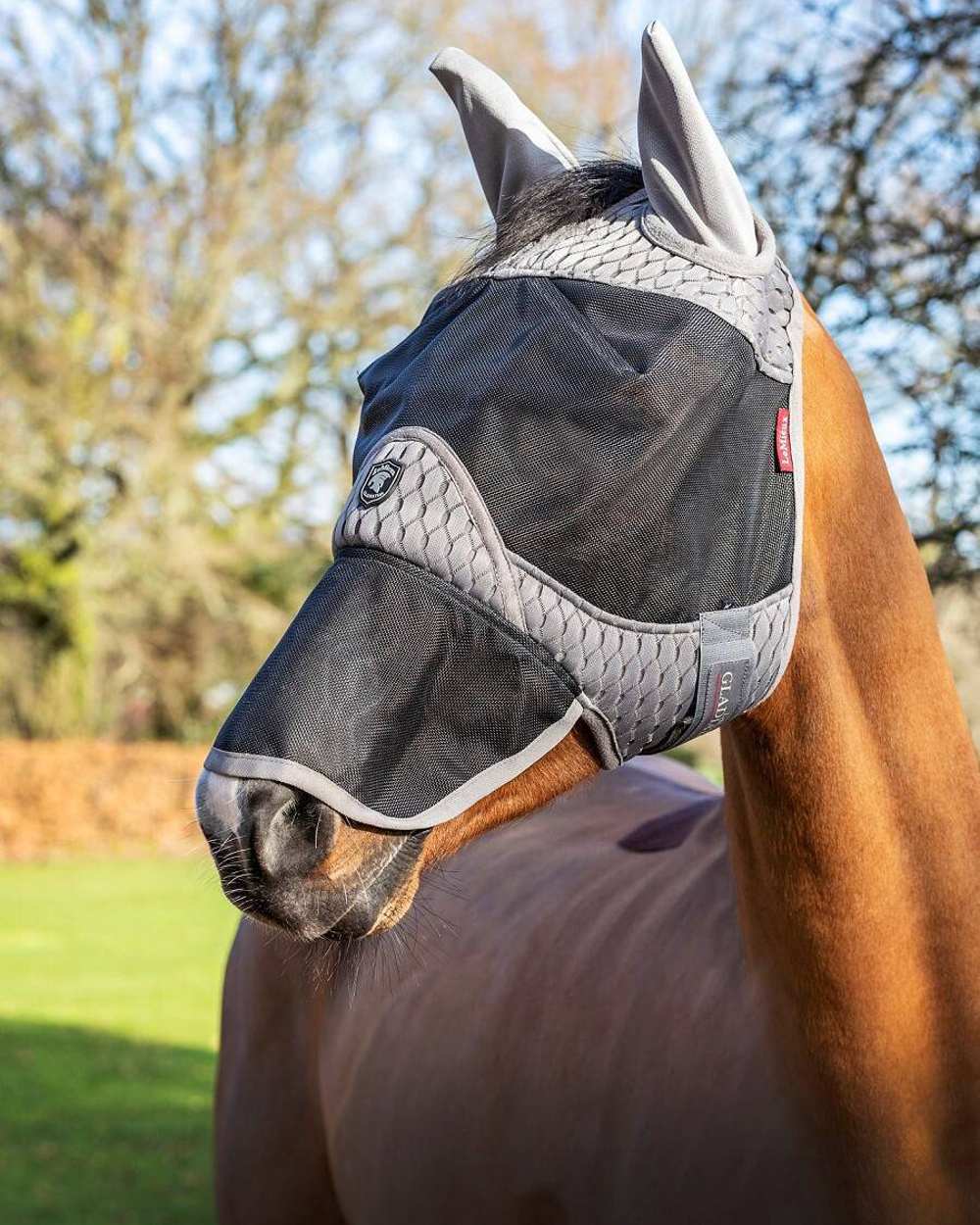 Grey coloured LeMieux Gladiator Full Fly Mask with tress in background 