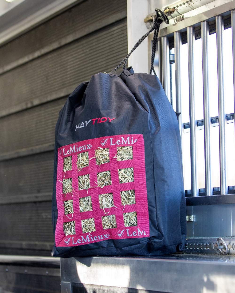 Black coloured LeMieux Hay Tidy Bag on stable wall background 