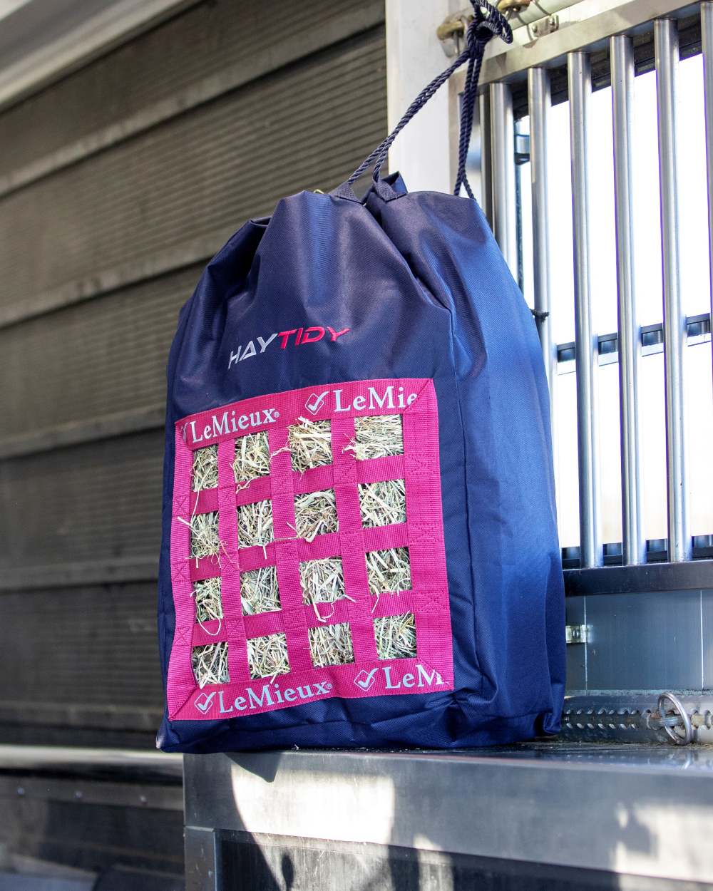 Navy coloured LeMieux Hay Tidy Bag on stable wall background 