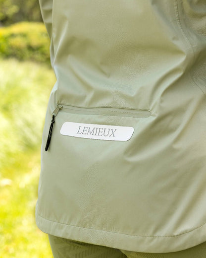 Fern coloured LeMieux Isla Short Waterproof Jacket on green background 