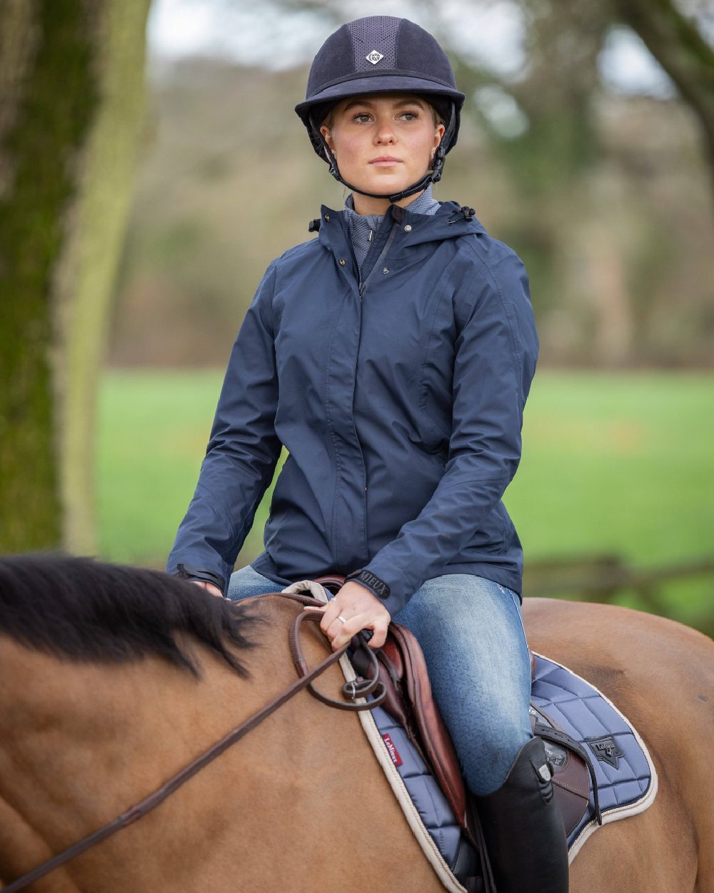 Navy coloured LeMieux Isla Short Waterproof Jacket on blurry background 