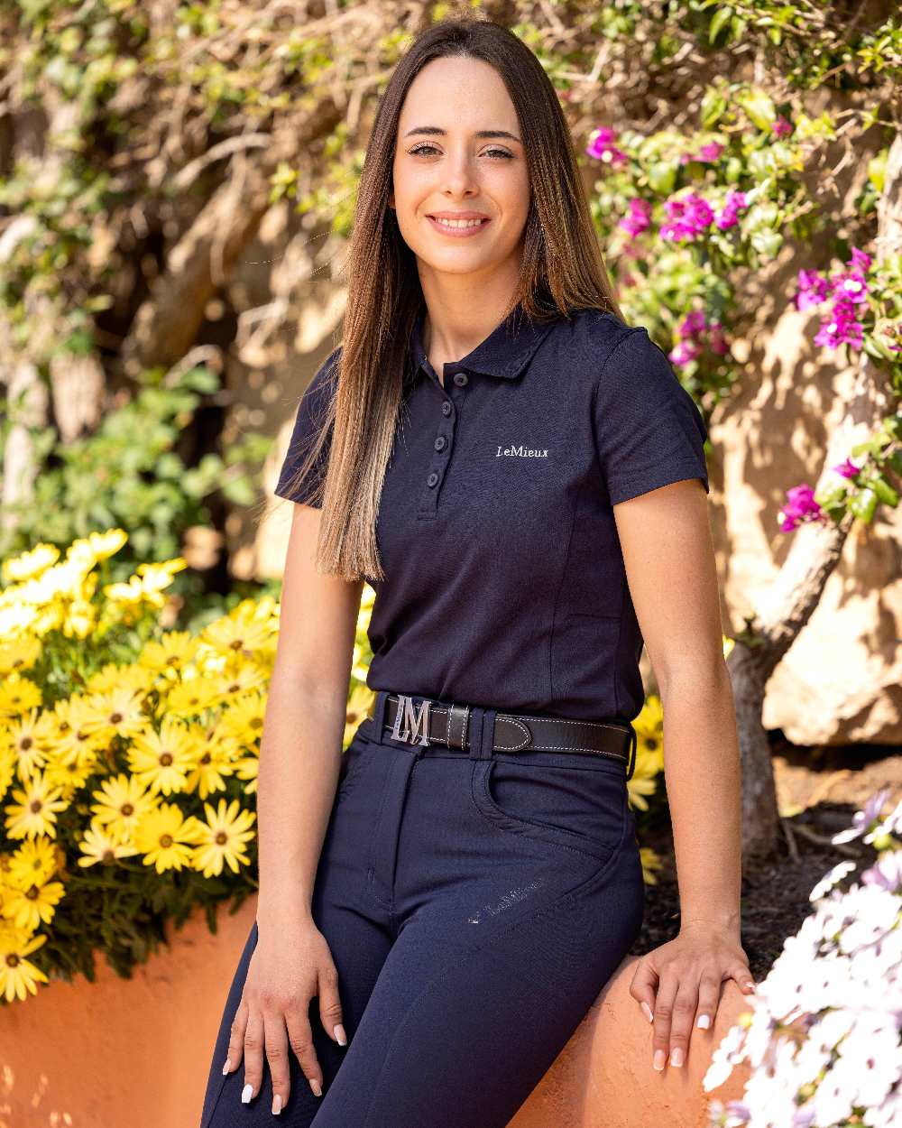 Navy coloured LeMieux Ladies Elite Polo Shirt II with plants in background 