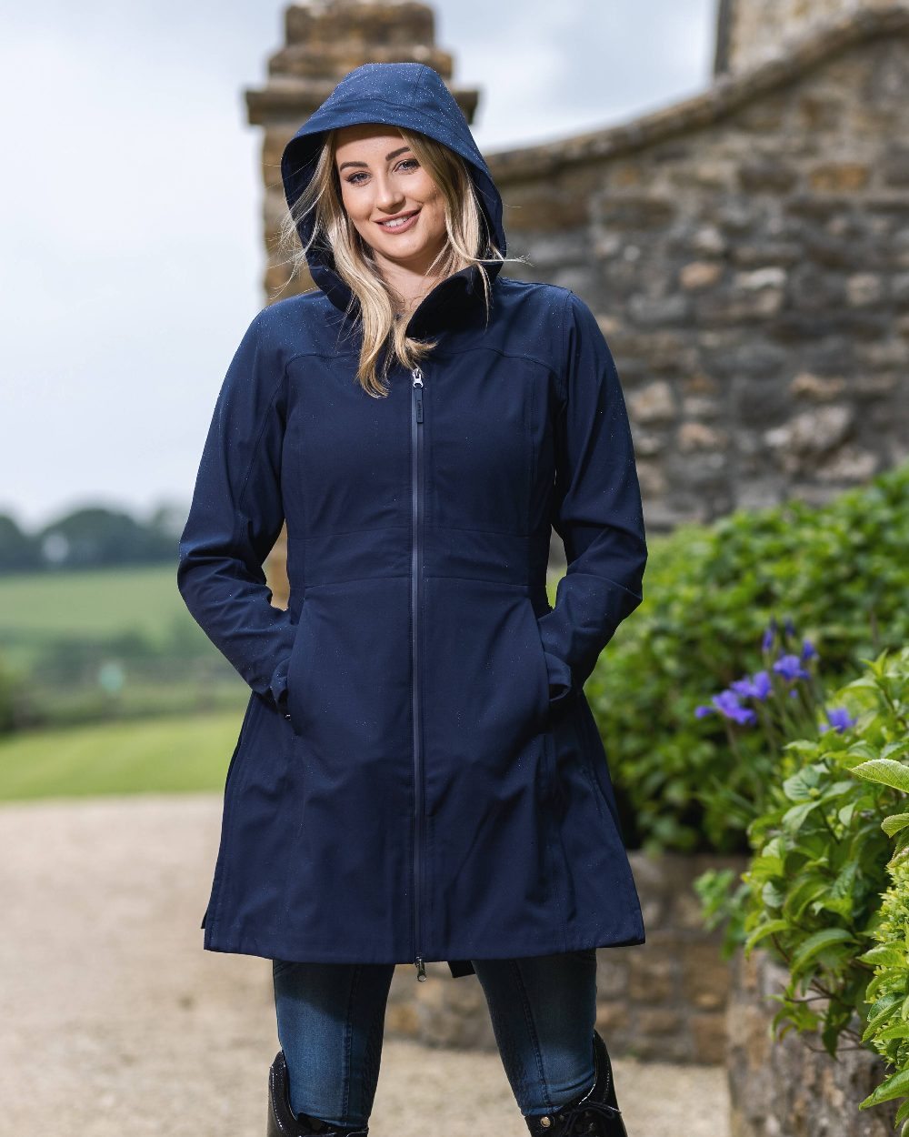 Navy coloured LeMieux Maisie Lightweight Riding Jacket with plants in background 