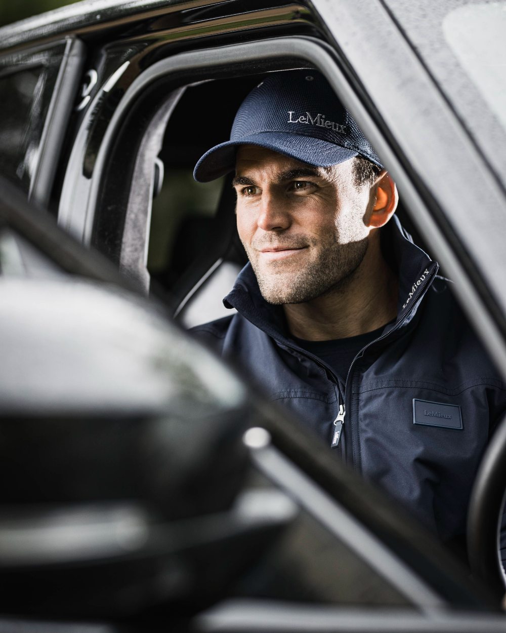 Navy coloured LeMieux Mesh Baseball Cap with car in background 