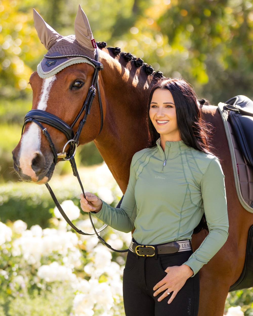 Thyme coloured LeMieux Mia Mesh Long Sleeve Base Layer on blurry tree background 