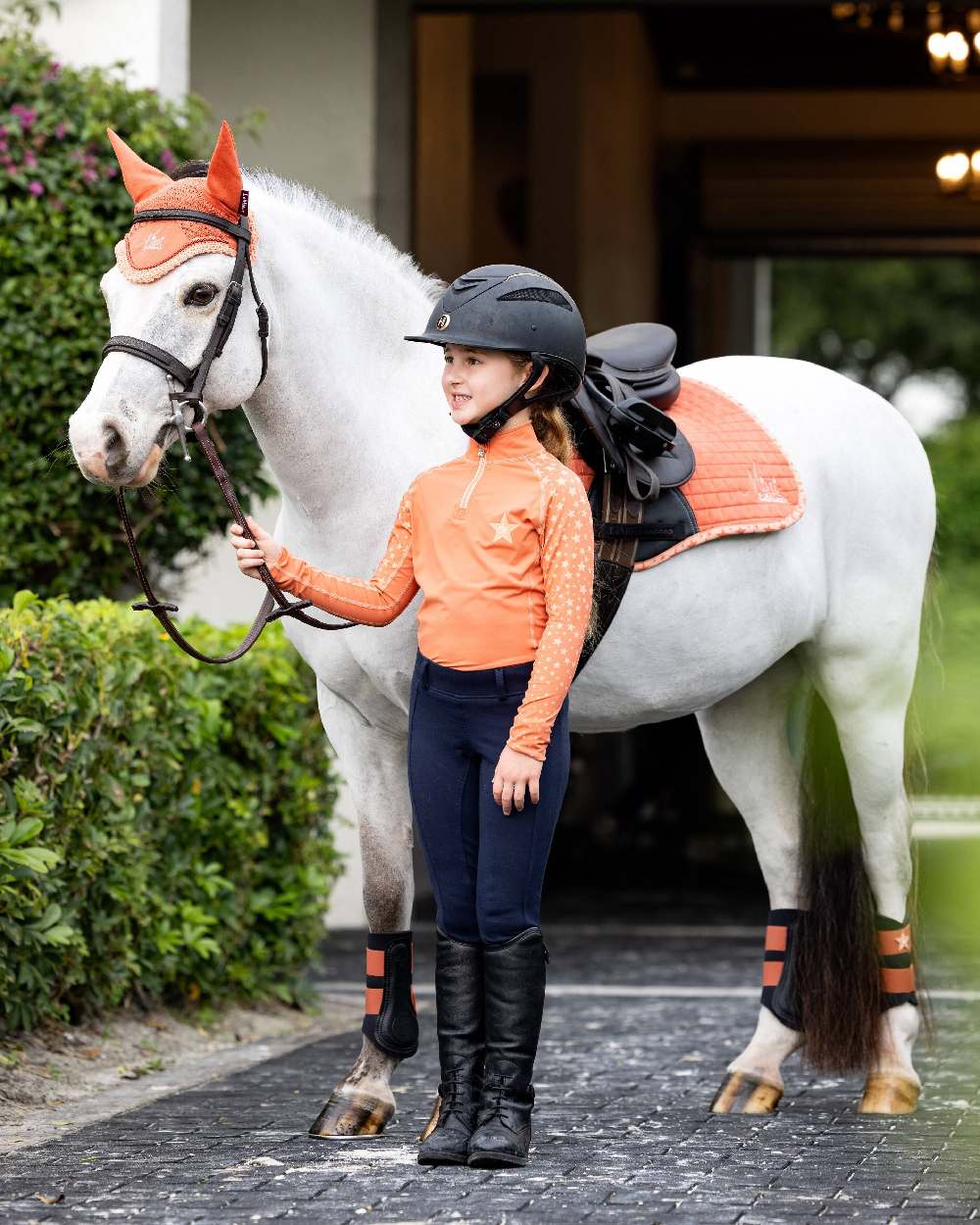 Apricot coloured LeMieux Mini Base Layers with plants in background 