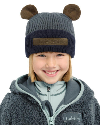 Petrol Coloured LeMieux Mini Bear Beanie On A Street Background 