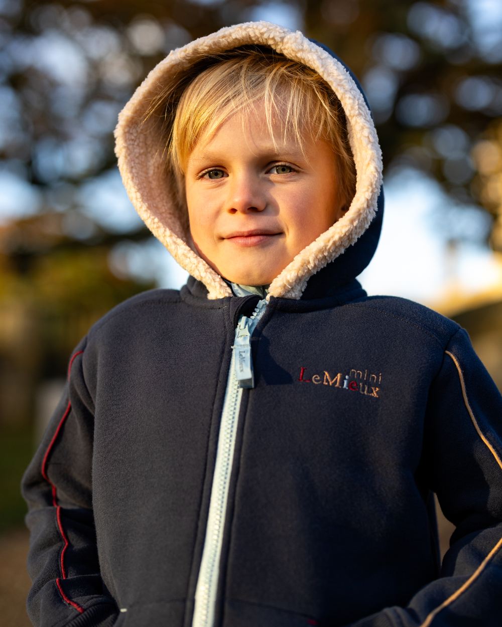 Navy Coloured LeMieux Mini Charlie Lined Hoodie On A Blurry Background 