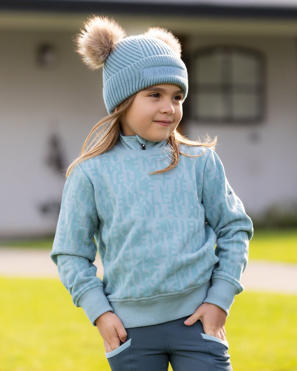 Glacier Coloured LeMieux Mini Clara Beanie On A Outer Yard Background 