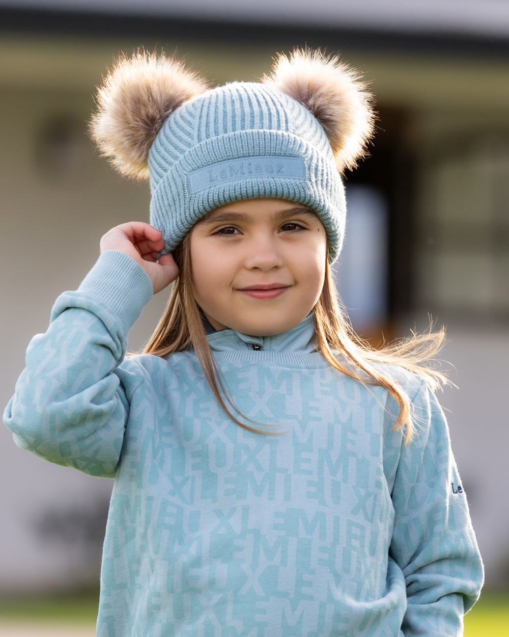 Glacier Coloured LeMieux Mini Clara Beanie On A Outer Yard Background 