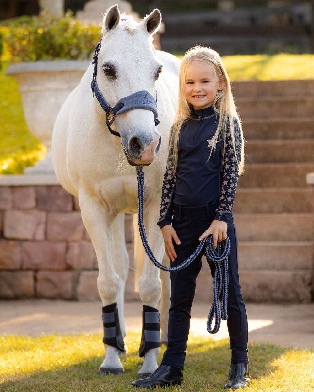 Indigo coloured LeMieux Mini Reflective Print Base Layer with horse in background 