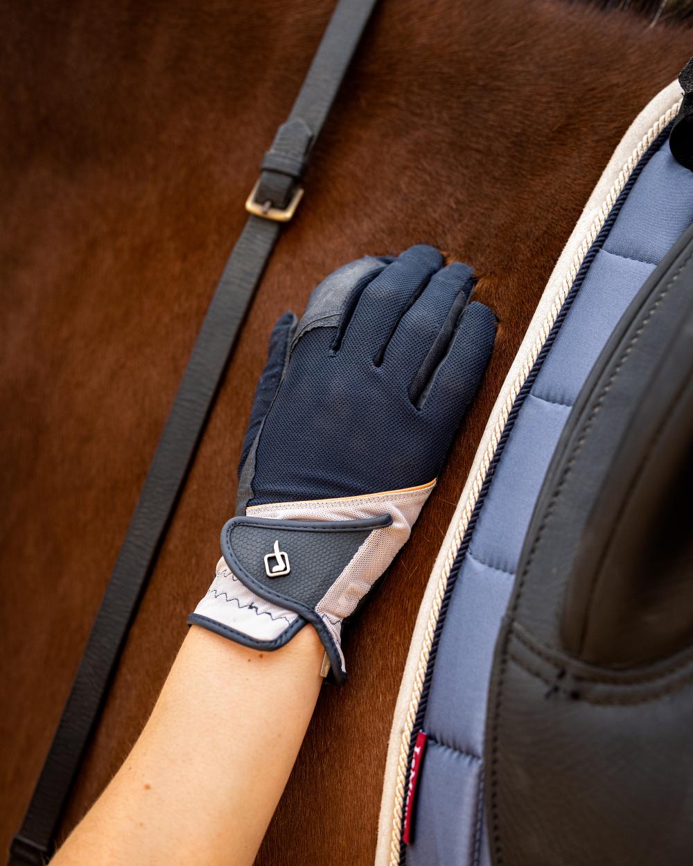 Apricot coloured LeMieux Pro Mesh Gloves with horse in background 