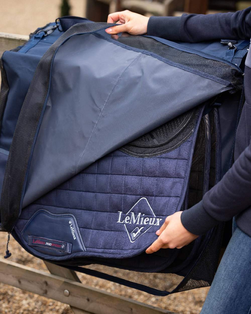 Navy coloured LeMieux Saddle Pad Carry Bag on blurry background 