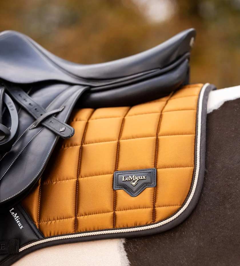 LeMieux Saddle pad in Ginger gold with a leather saddle numnah on a horse.