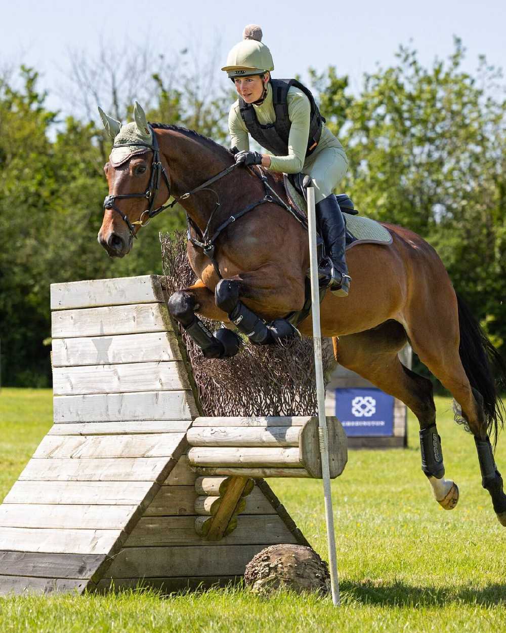 Fern coloured LeMieux Suede Close Contact Squares on show jumping background 