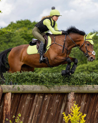 Kiwi coloured LeMieux Suede Close Contact Squares on show jumping background 