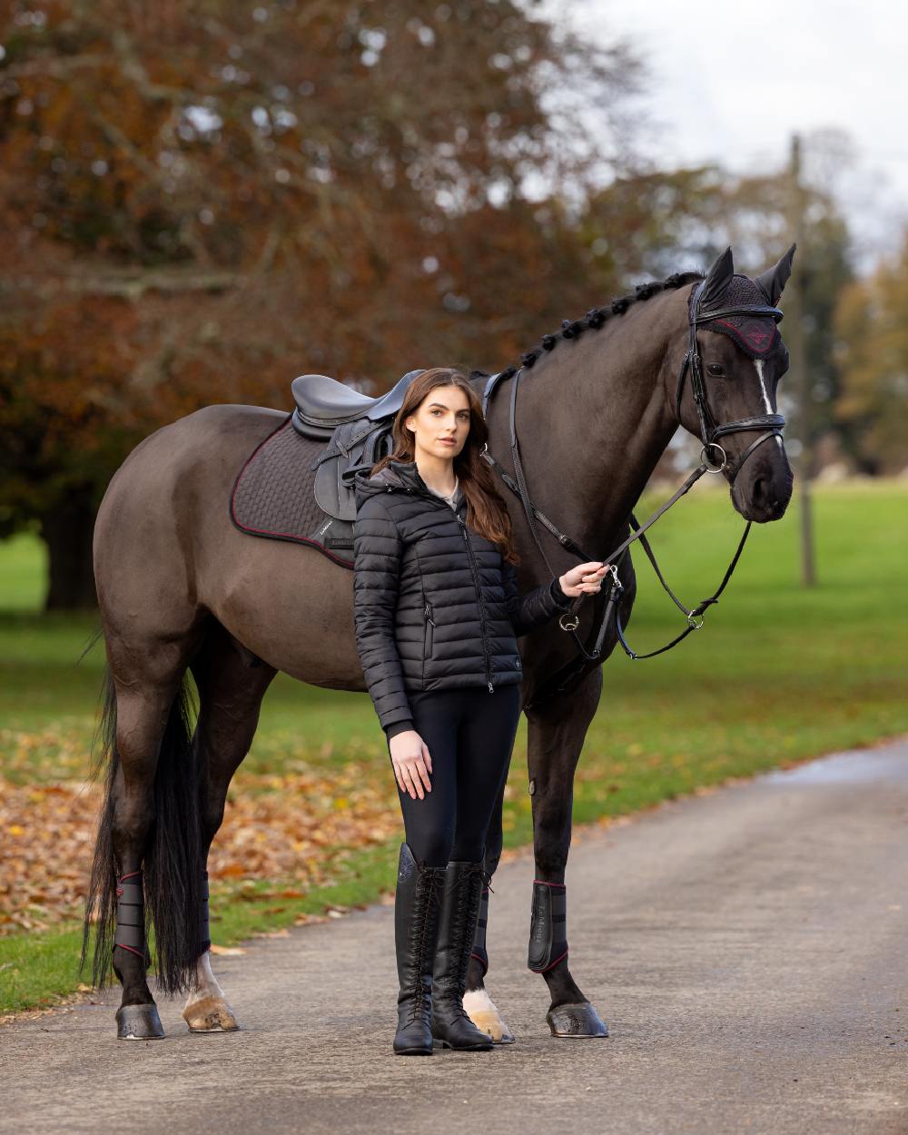 Black Coloured LeMieux Tilly Hooded Puffer Jacket On A Outer Yard Background 