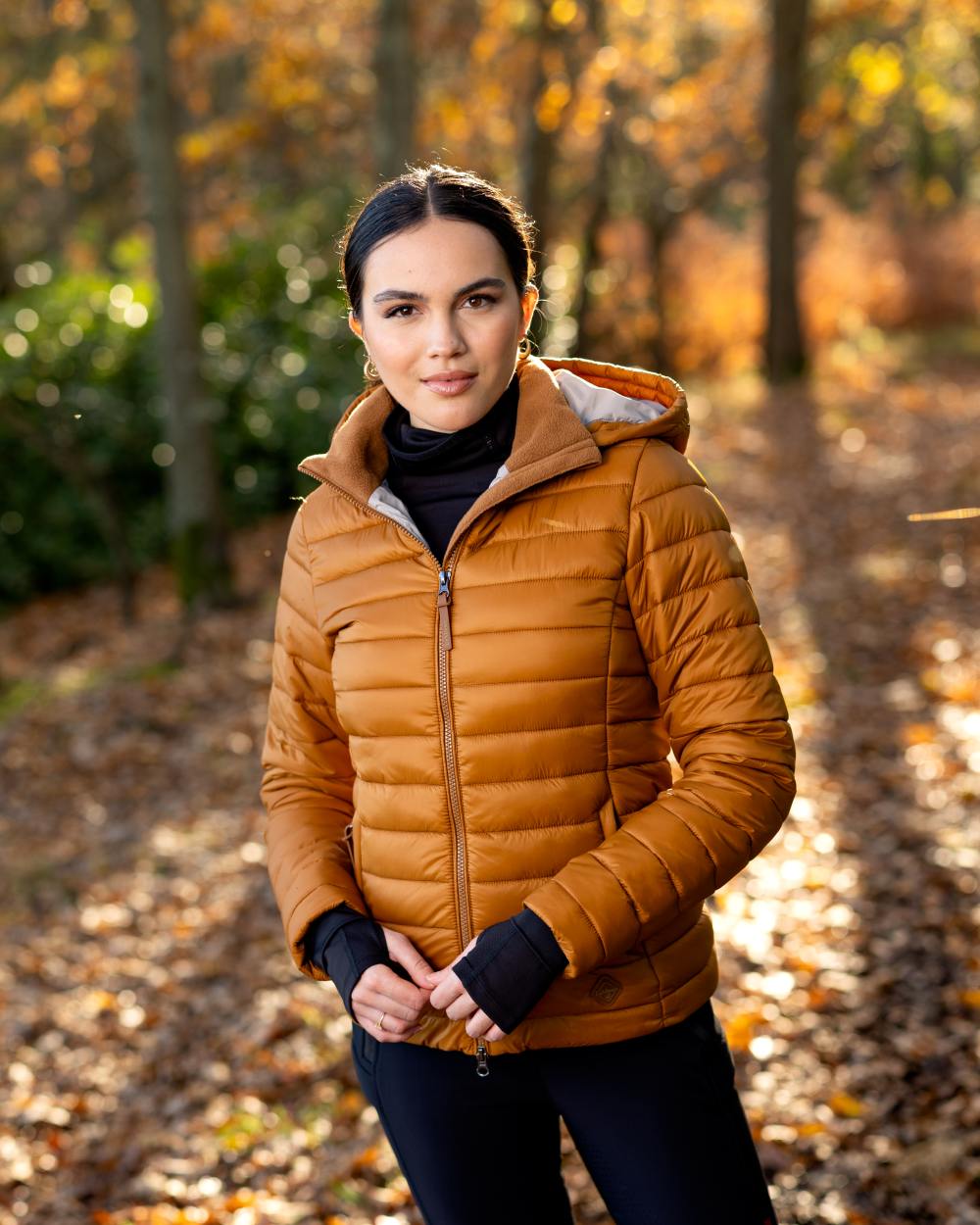 Ginger Coloured LeMieux Tilly Hooded Puffer Jacket On A Forest Background 