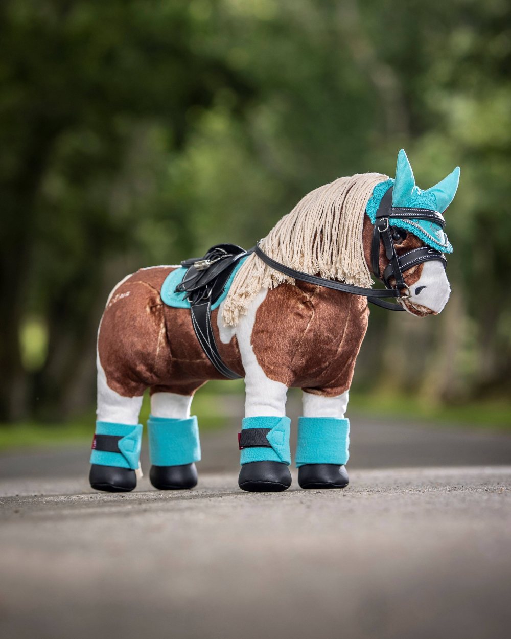 Azure coloured LeMieux Toy Pony Fly Hood on blurry green background 