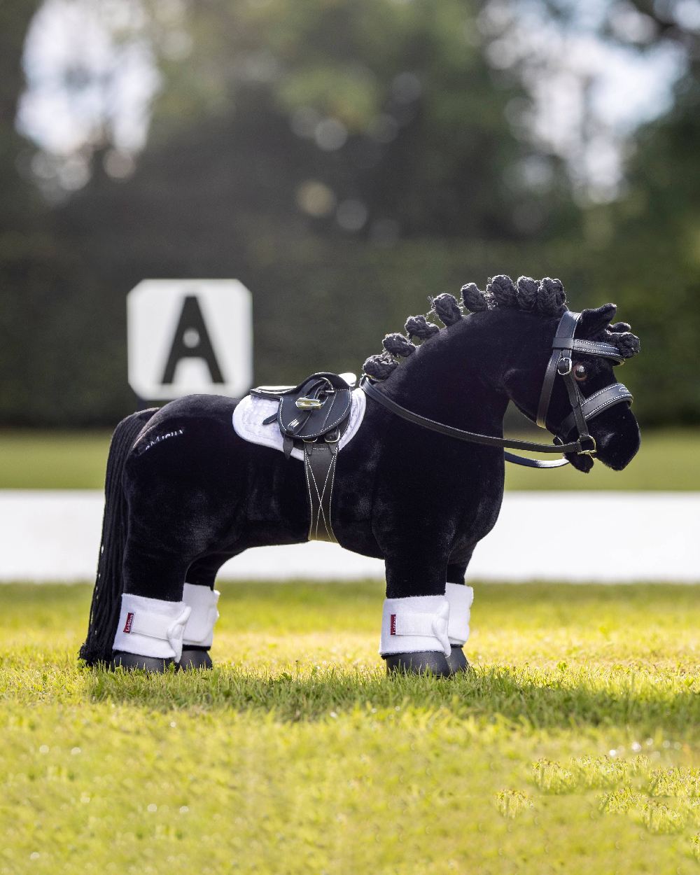 Black coloured LeMieux Toy Pony Saddle on blurry green background 