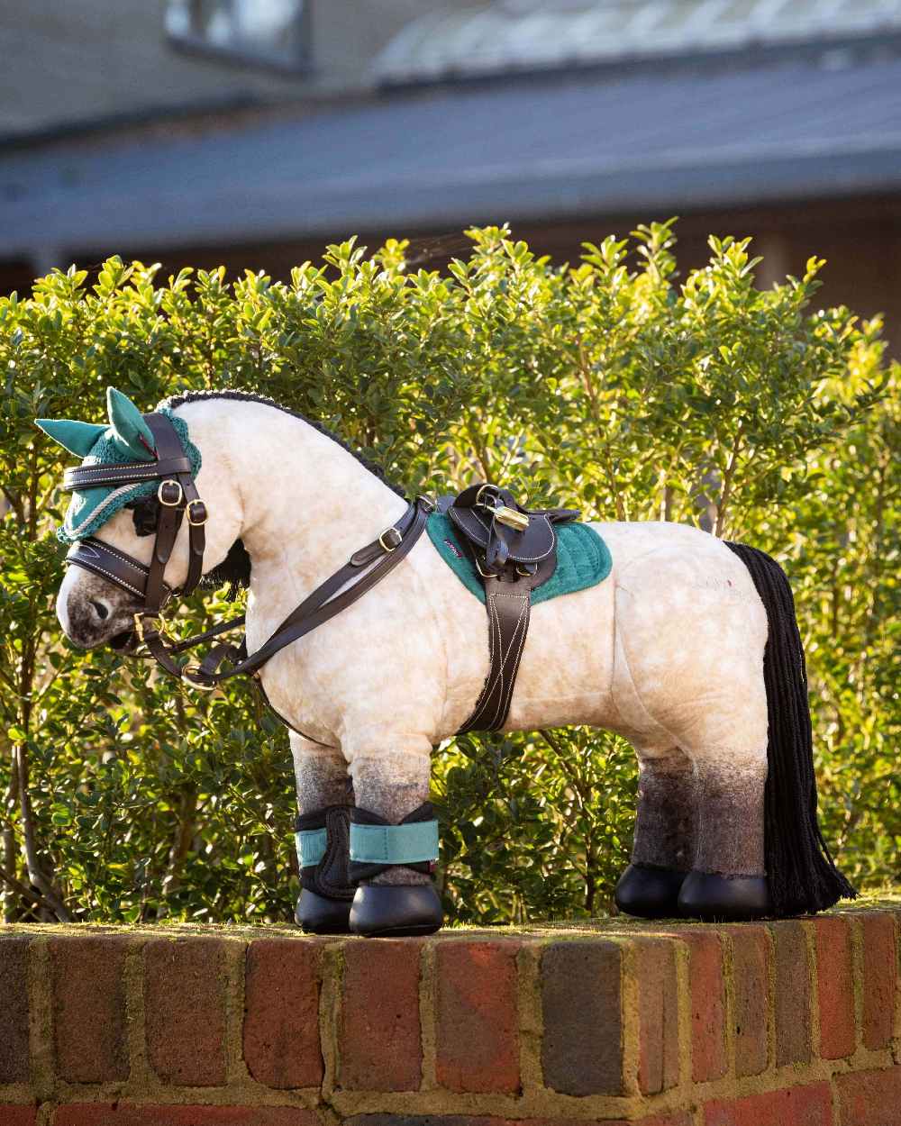 Brown coloured LeMieux Toy Pony Saddle with bush in background 